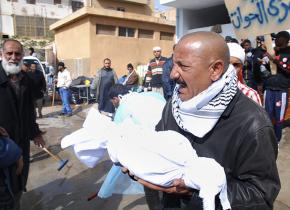 A man carries the partial remains of a fellow protester from a hospital in Benghazi